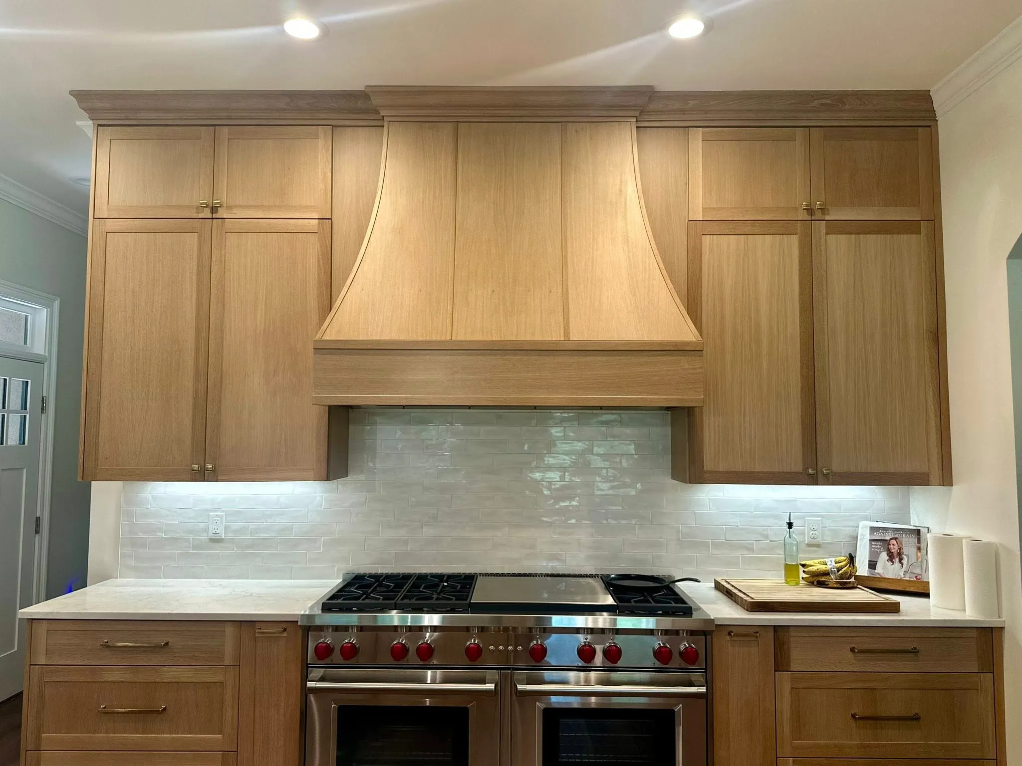 Custom light oak kitchen cabinetry and range hood by Alvarez Construction